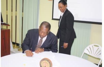 The President of Caribbean Court of Justice, the Right Honourable Sir Dennis Byron (seated), signs the revised rules governing the Original Jurisdiction.  The signing took place on 21 April 2017 at an event held by the Court in celebration of its 12th anniversary.  The CCJ’s Registrar and Marshal, Mrs. Jacqueline Graham, who was a part of the review committee, watches as the document is authorised. 